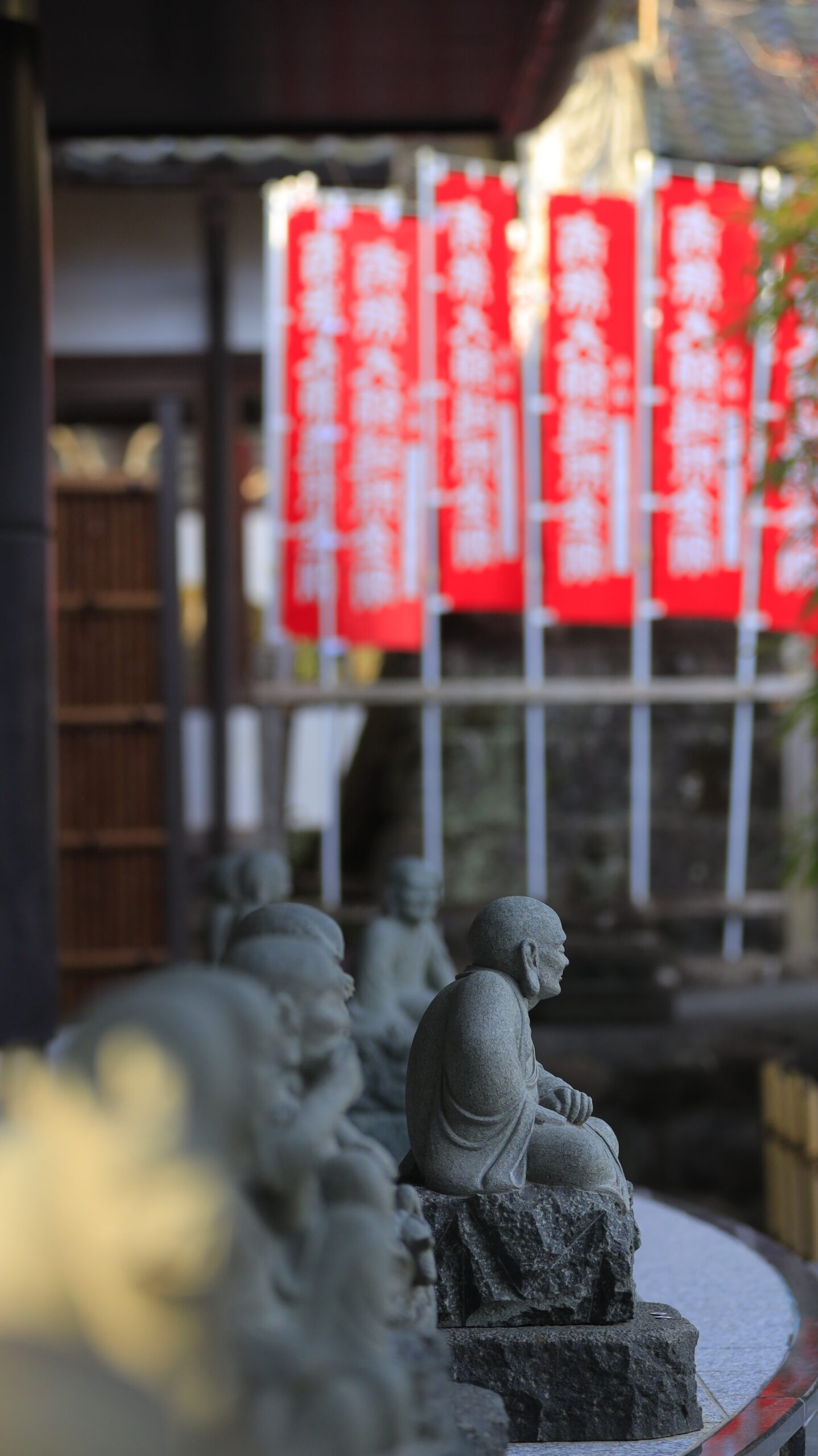 静岡県伊豆市・修禅寺で、奥にある石像と旗を組み合わせ寺内の雰囲気を伝える一枚