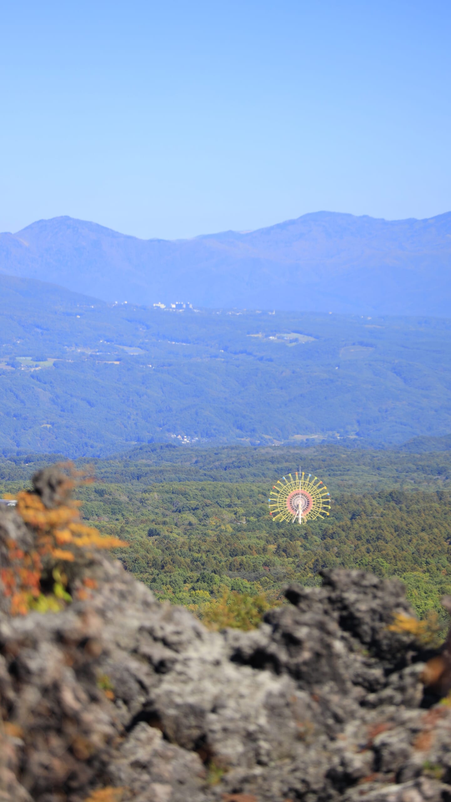 鬼押出し園で手前の溶岩と遠くの山々、観覧車を組み合わせた風景