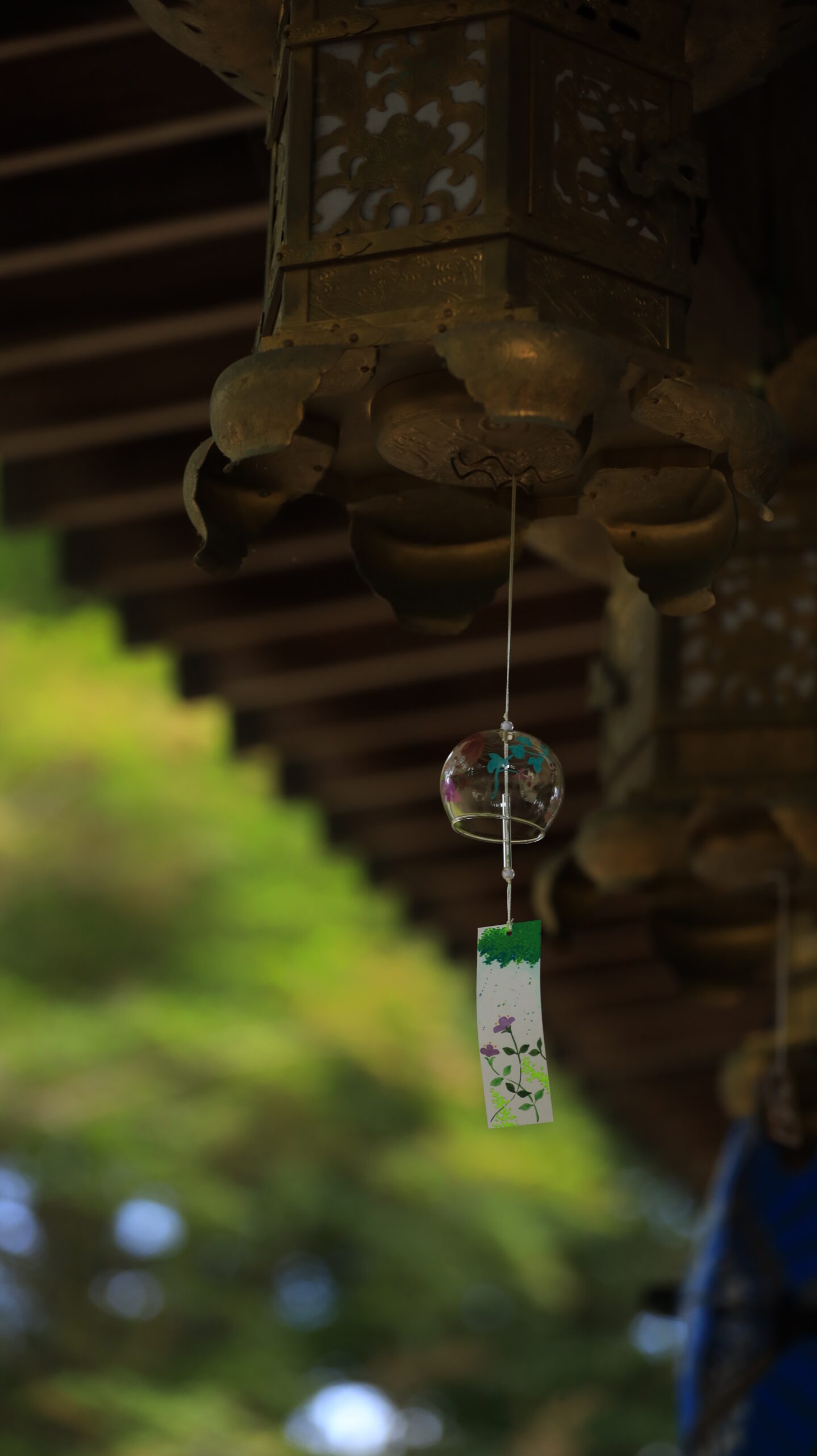 大宝八幡宮で奥の緑をぼかして撮影した金属製釣灯篭の下の風鈴