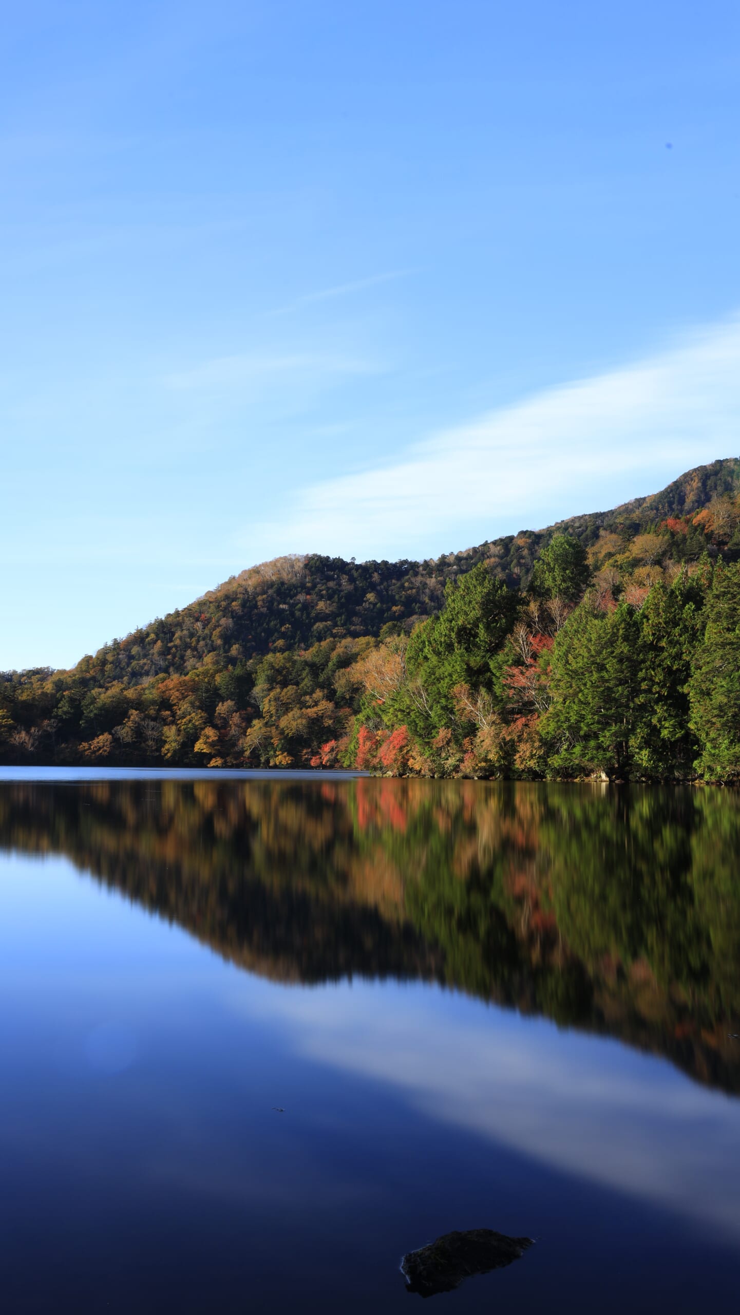 奥日光の湯ノ湖で、広角気味の構図とスローシャッターで捉えた、湖畔の紅葉と滑らかな水面に映るリフレクション
