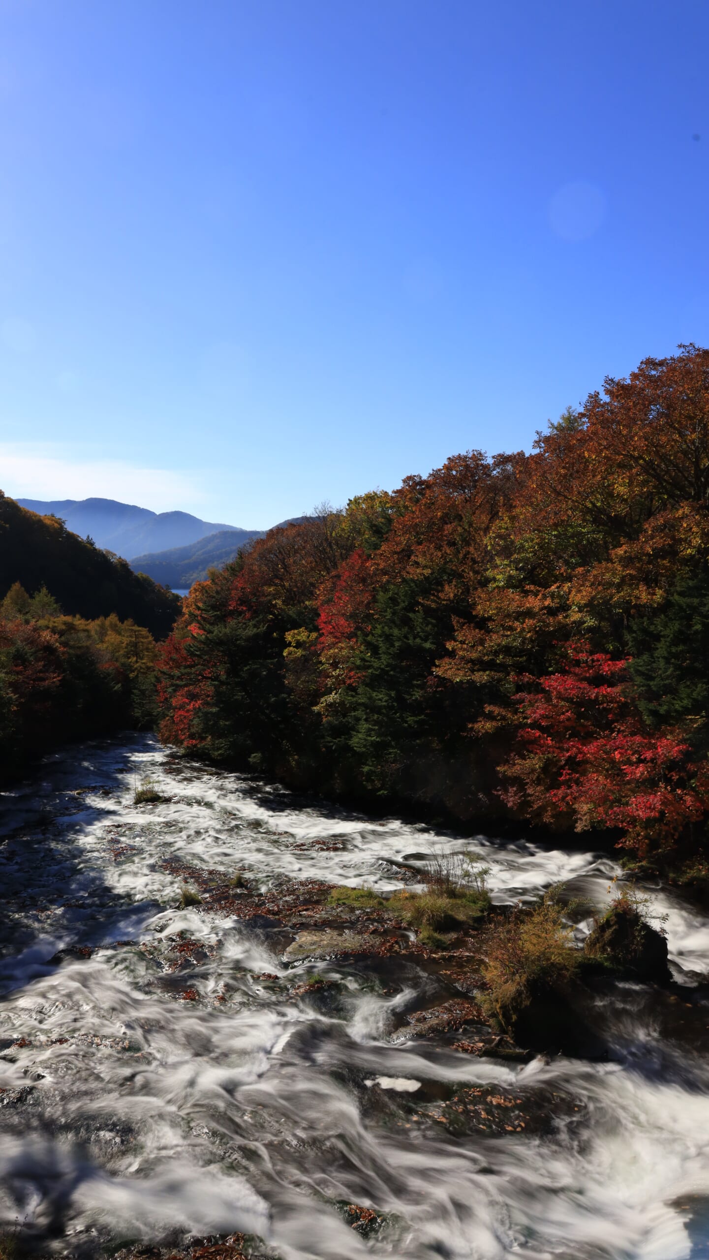 奥日光の龍頭の滝で、上流から流れる滝の水をスローシャッターで滑らかに表現した、周囲の紅葉との秋景色
