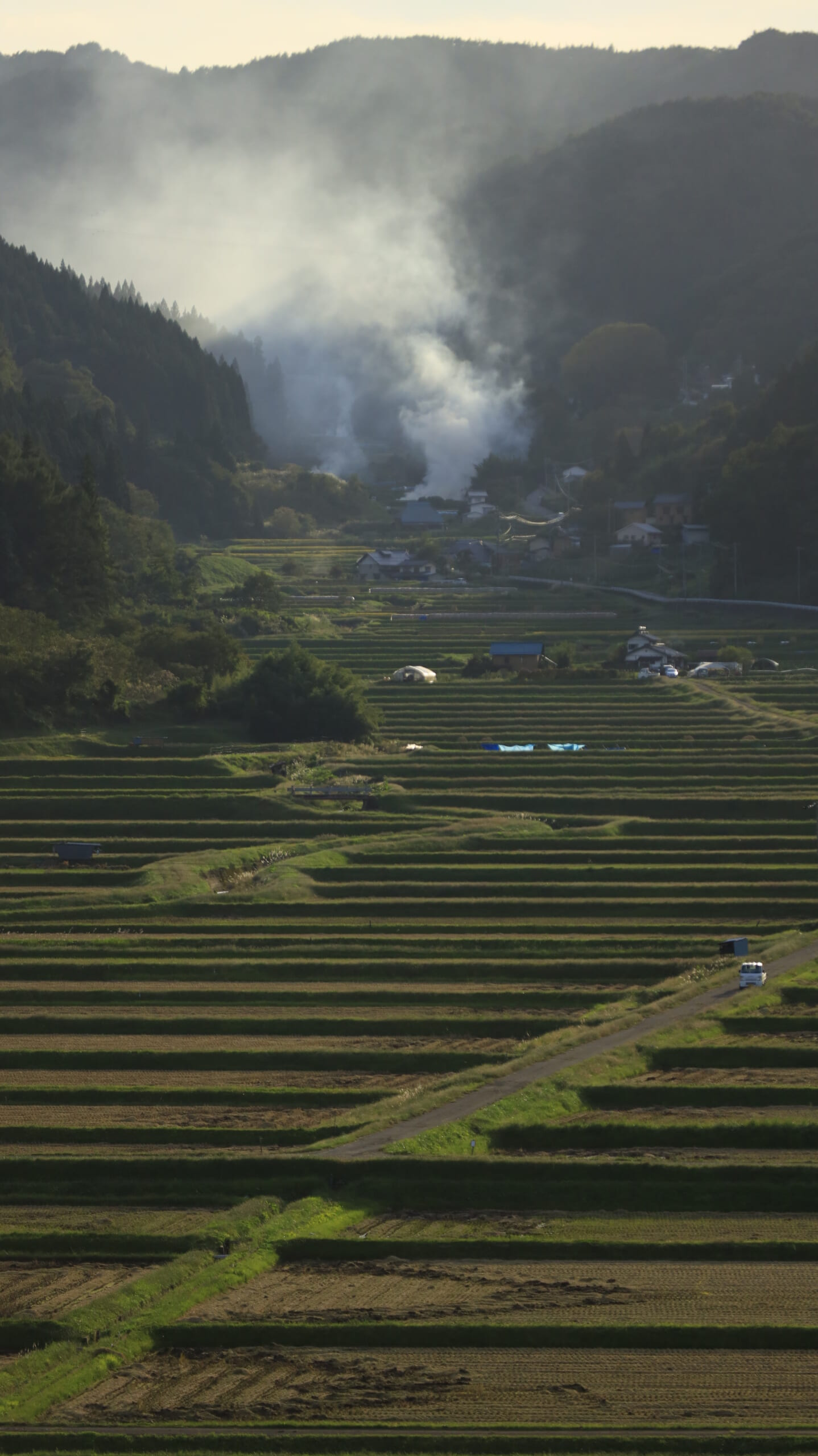 長野県内の夕暮れの空と田んぼ、焚き火から立ち上る煙
